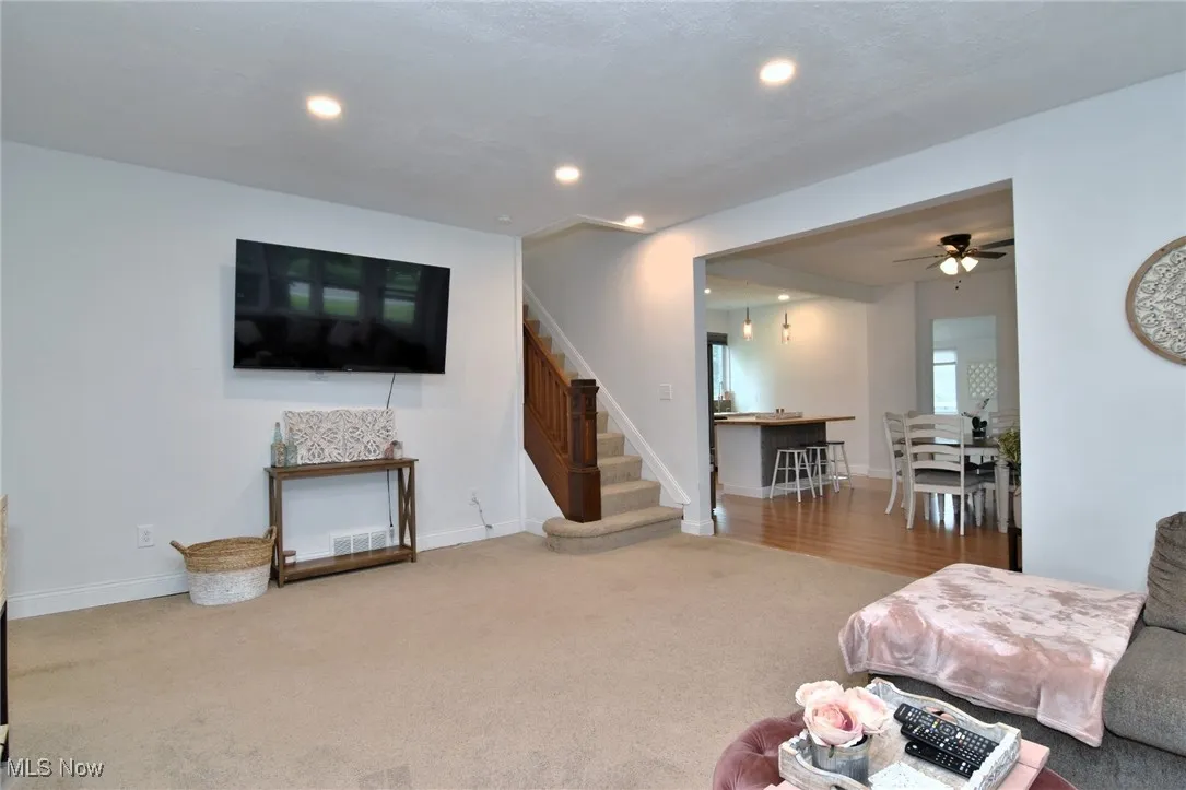 Living area with recessed lighting, light colored carpet, stairway, and a ceiling fan