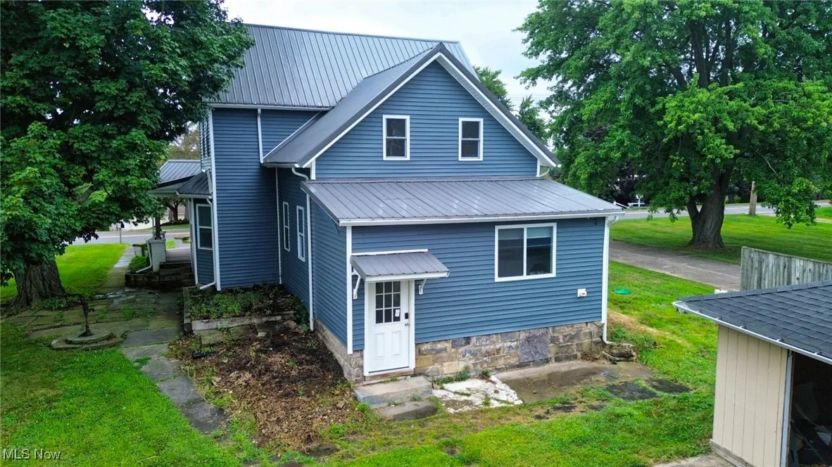 Back of house with a yard and a metal roof