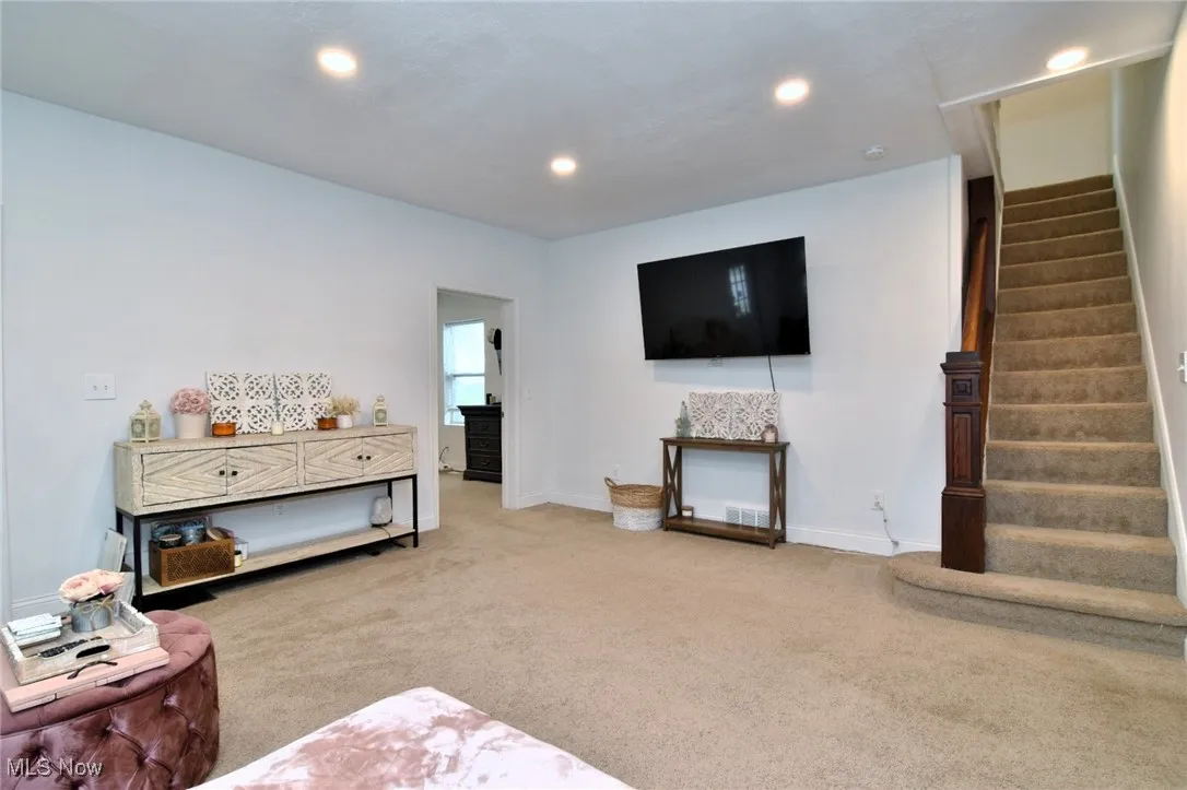 Living area featuring light colored carpet, recessed lighting, and stairway