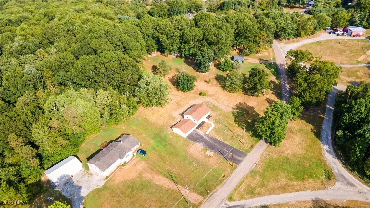 Aerial view of property and surrounding area featuring a forest