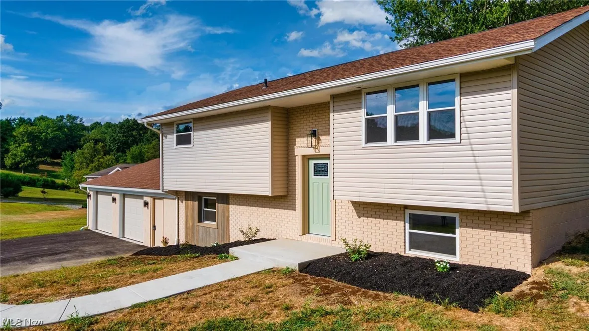 Bi-level home with brick siding, a front yard, asphalt driveway, and a garage