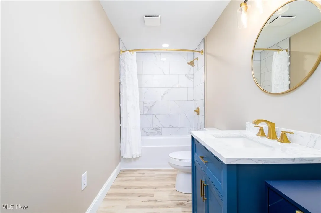 Bathroom with shower / bath combo with shower curtain, vanity, light wood-style flooring, and recessed lighting