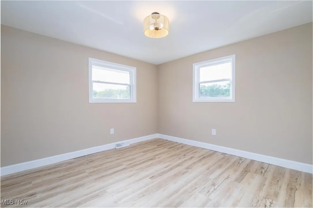 Unfurnished room with light wood finished floors and healthy amount of natural light