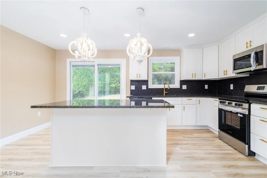 Kitchen with stainless steel appliances, decorative light fixtures, decorative backsplash, a center island, and recessed lighting