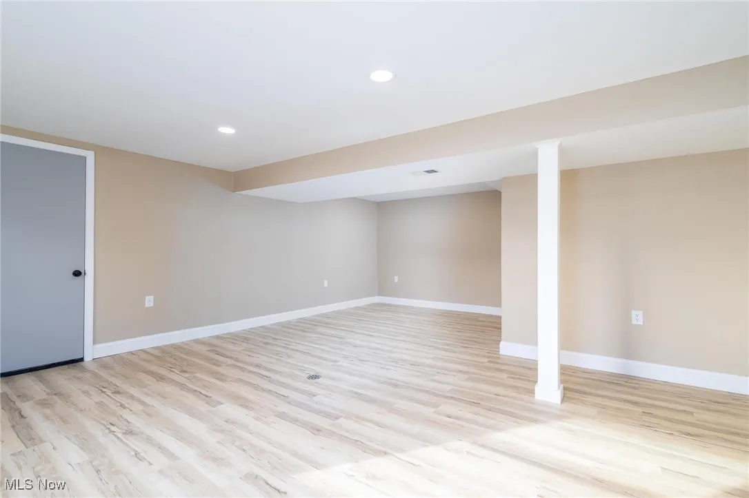 Finished below grade area featuring light wood-style flooring and recessed lighting