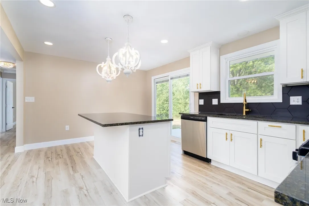 Kitchen featuring decorative backsplash, decorative light fixtures, a center island, white cabinets, and recessed lighting