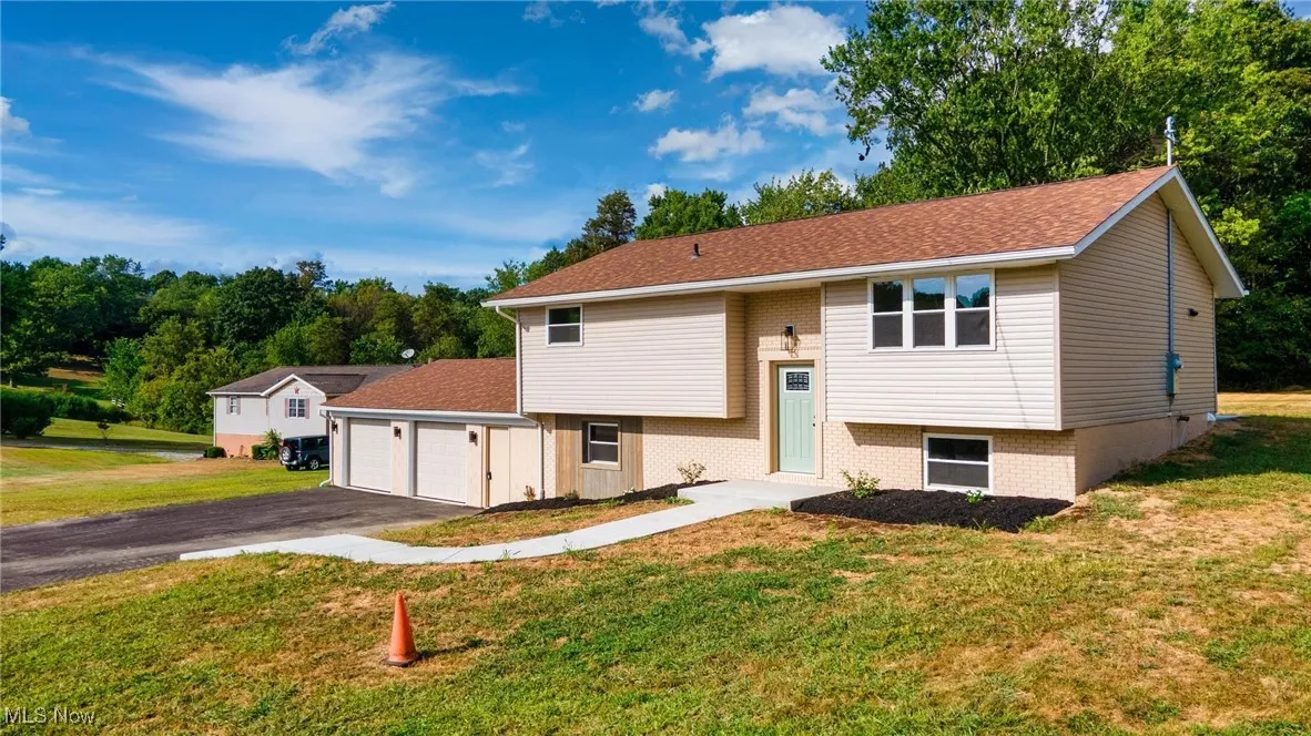 Raised ranch with brick siding, a front yard, and asphalt driveway