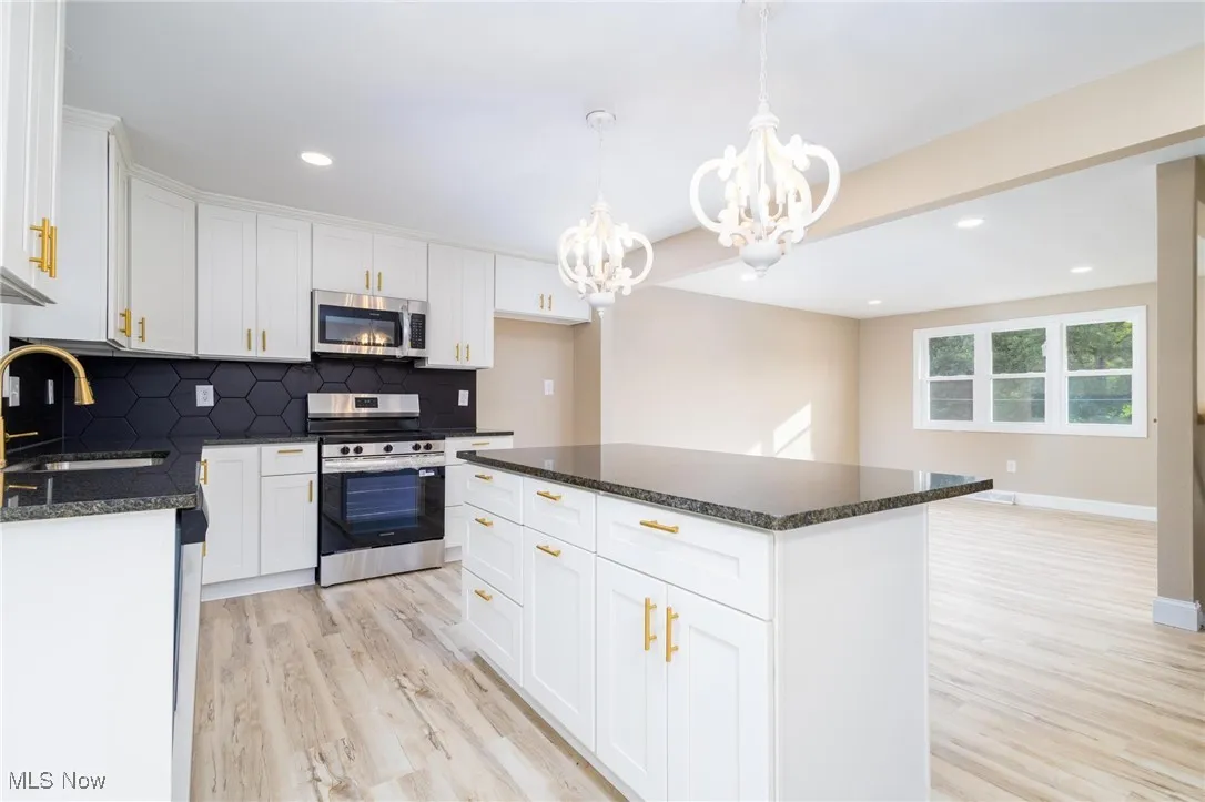 Kitchen featuring stainless steel appliances, white cabinetry, dark stone counters, tasteful backsplash, and recessed lighting