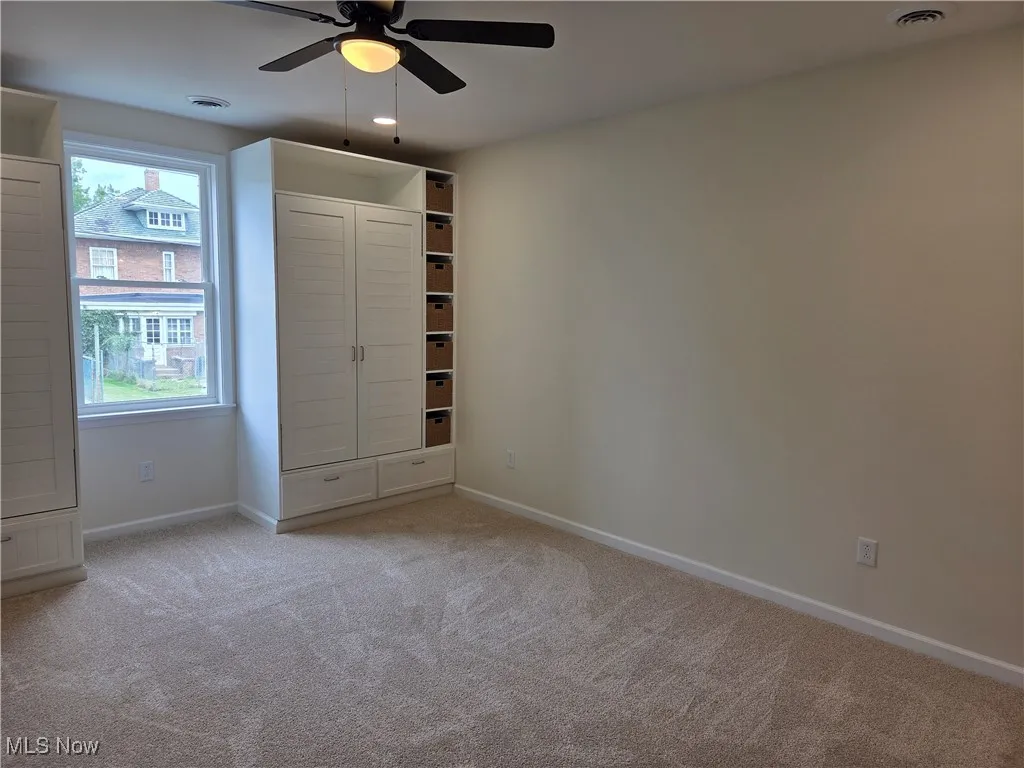 Unfurnished bedroom with light colored carpet and a ceiling fan