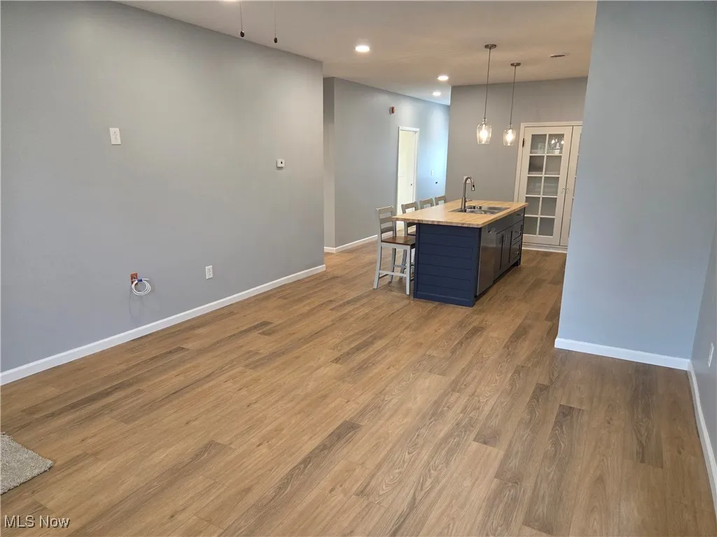 Kitchen featuring a kitchen island with sink, a kitchen breakfast bar, hanging light fixtures, recessed lighting, and dark wood-style floors