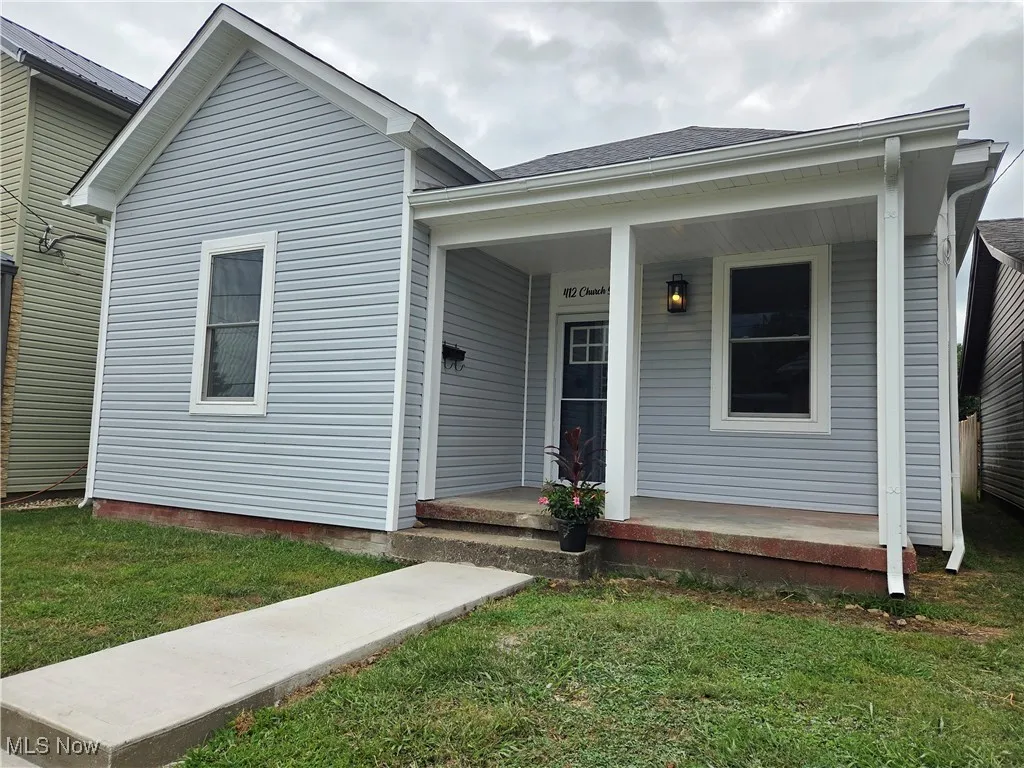 View of front of house with covered porch and a front lawn