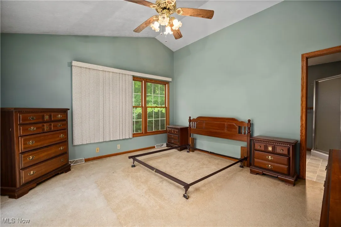 Bedroom featuring vaulted ceiling, light colored carpet, and ceiling fan