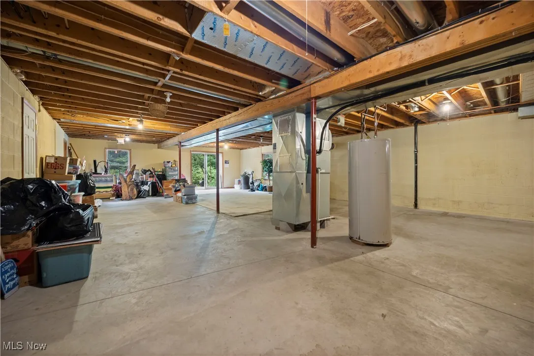 Basement area with heating unit, water heater, and doors to outside