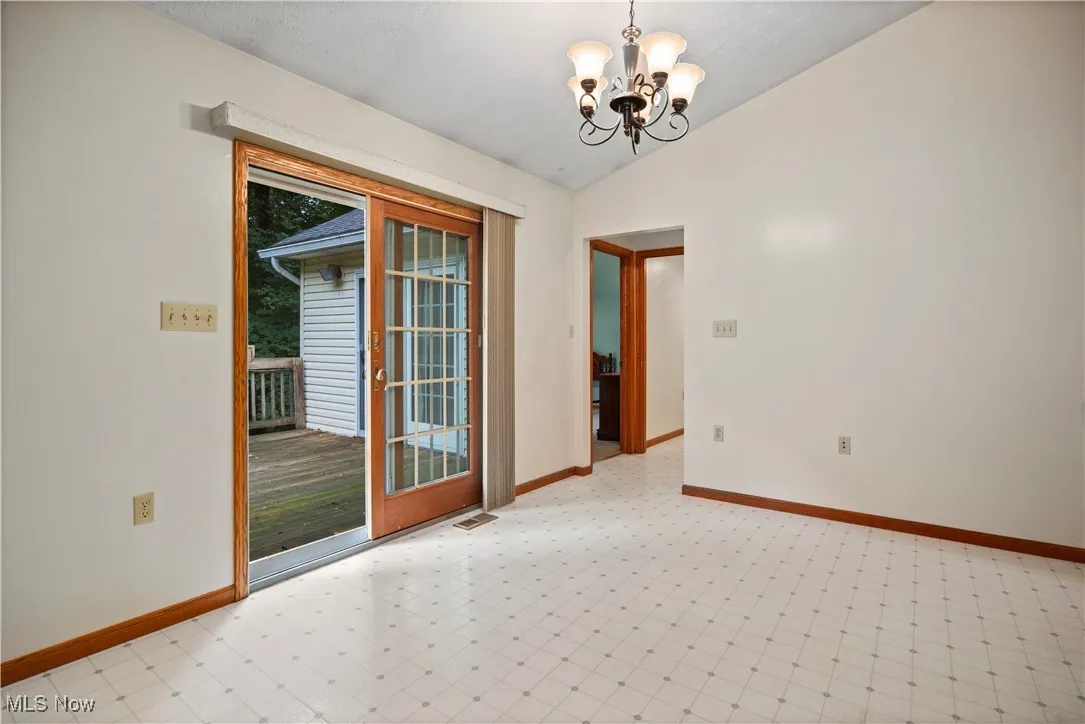 Unfurnished room featuring a chandelier and vaulted ceiling