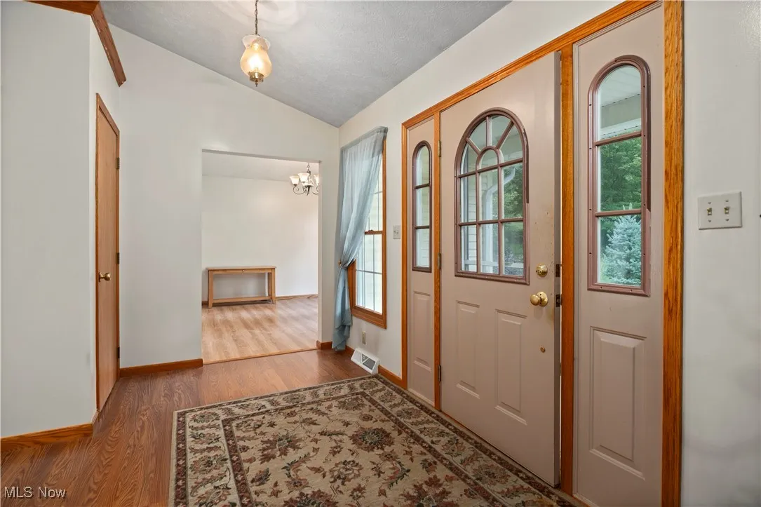 Foyer with floors,  vaulted ceiling, and a textured ceiling