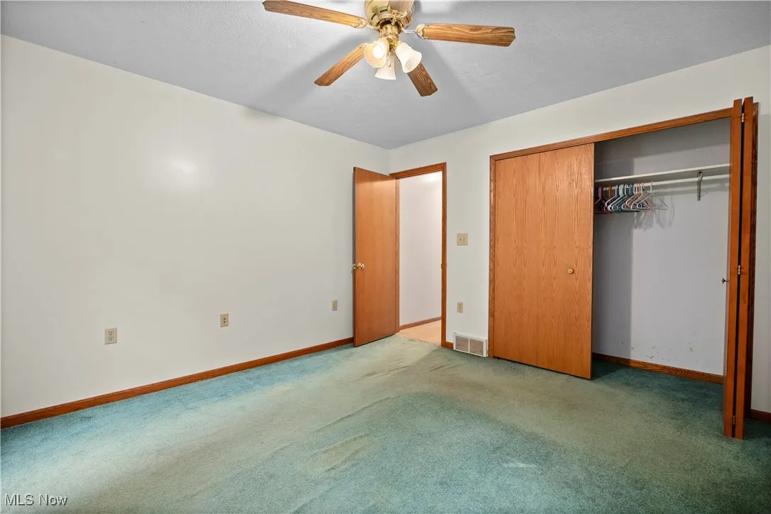 Unfurnished bedroom with carpet floors, ceiling fan, and a closet