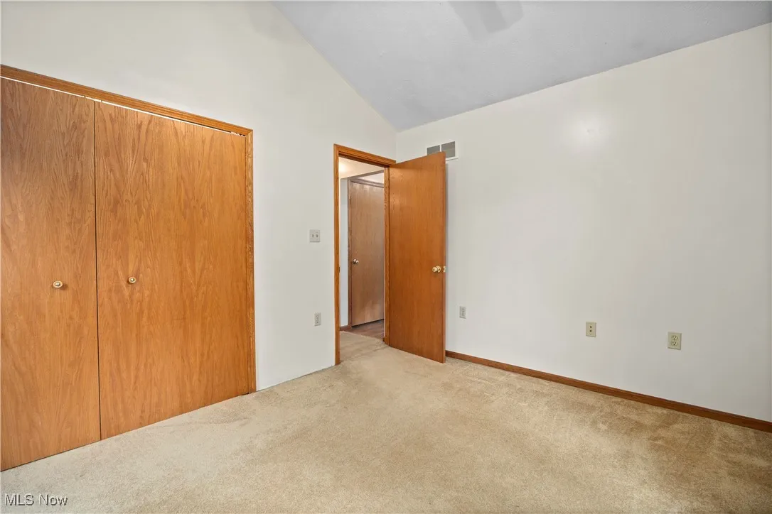 Unfurnished bedroom with a closet, lofted ceiling, and carpet flooring