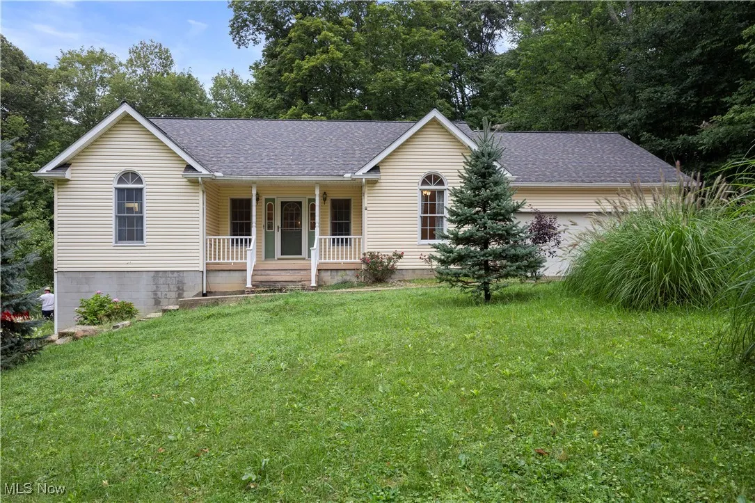 Ranch-style home featuring roof with shingles, covered porch, a front yard, and a garage