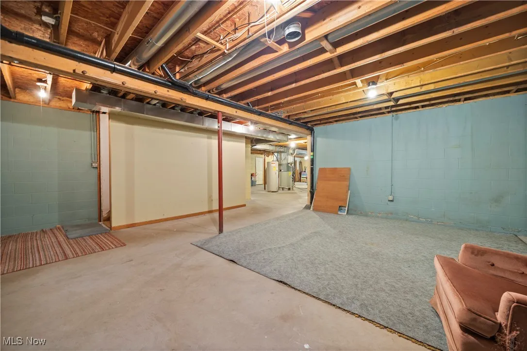Unfinished basement area featuring electric water heater and heating unit