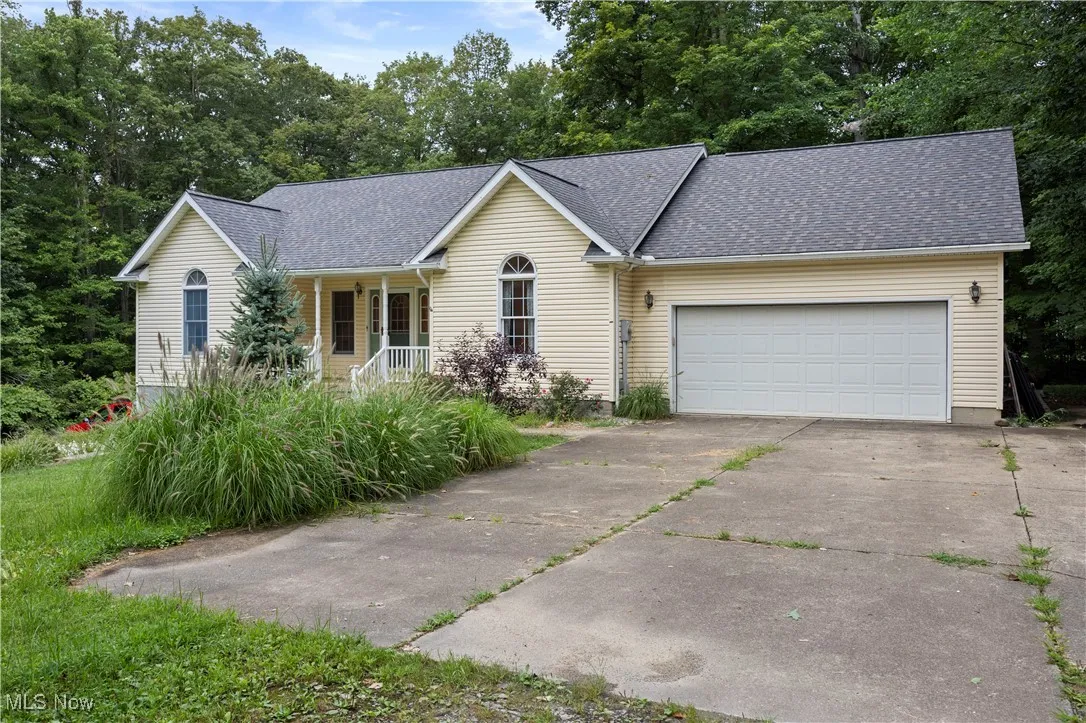 Ranch-style house featuring roof with shingles, a porch, driveway, and a garage