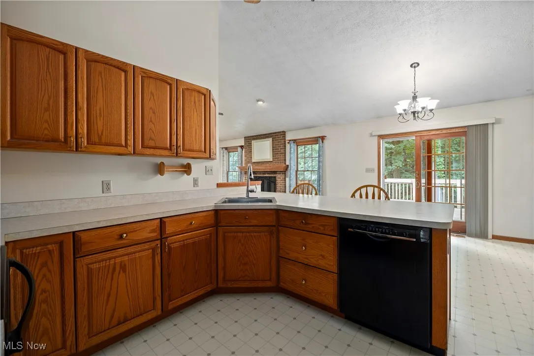 Kitchen featuring brown cabinets, black appliances, a peninsula, light countertops, and light flooring