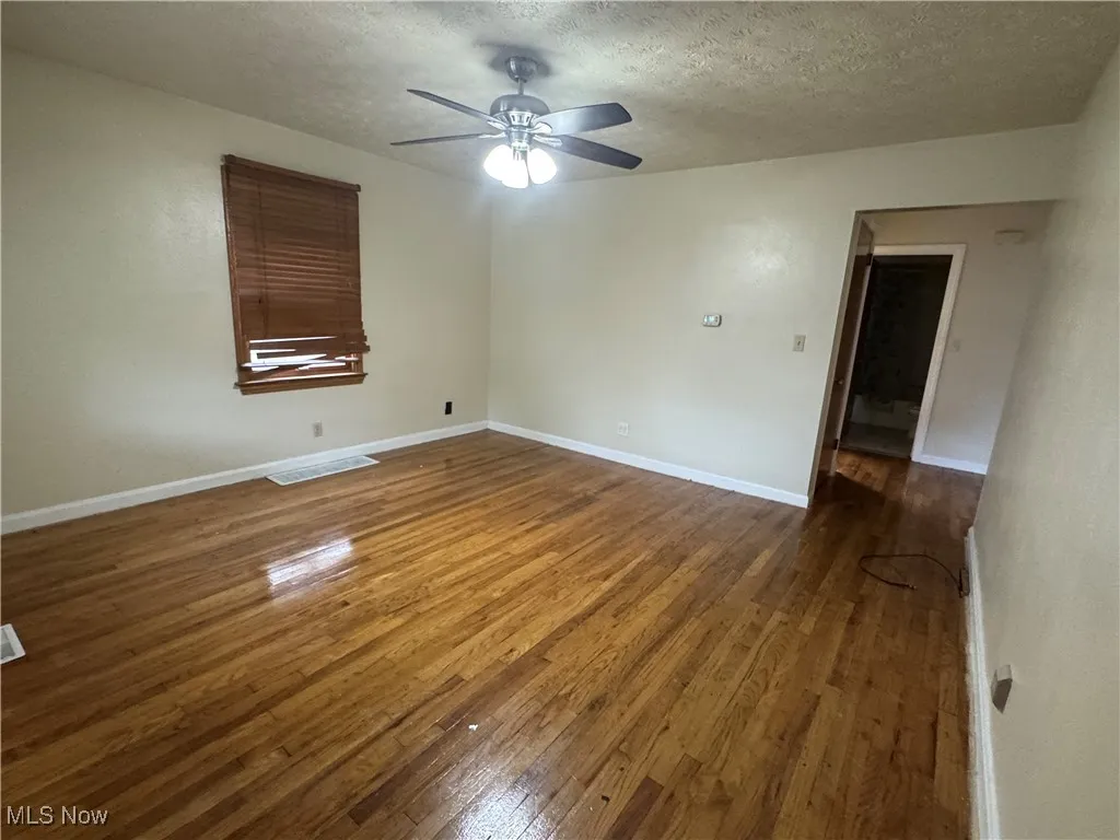Unfurnished room featuring dark wood-type flooring and a textured ceiling