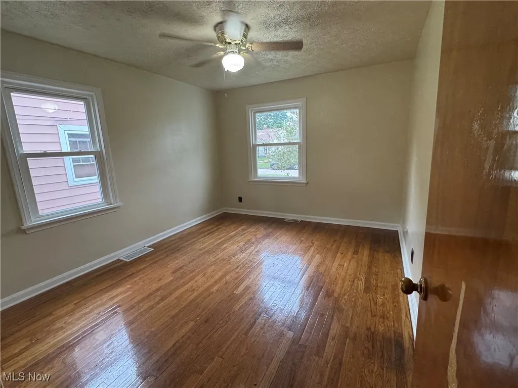 Unfurnished bedroom with hardwood / wood-style floors, a ceiling fan, and a textured ceiling