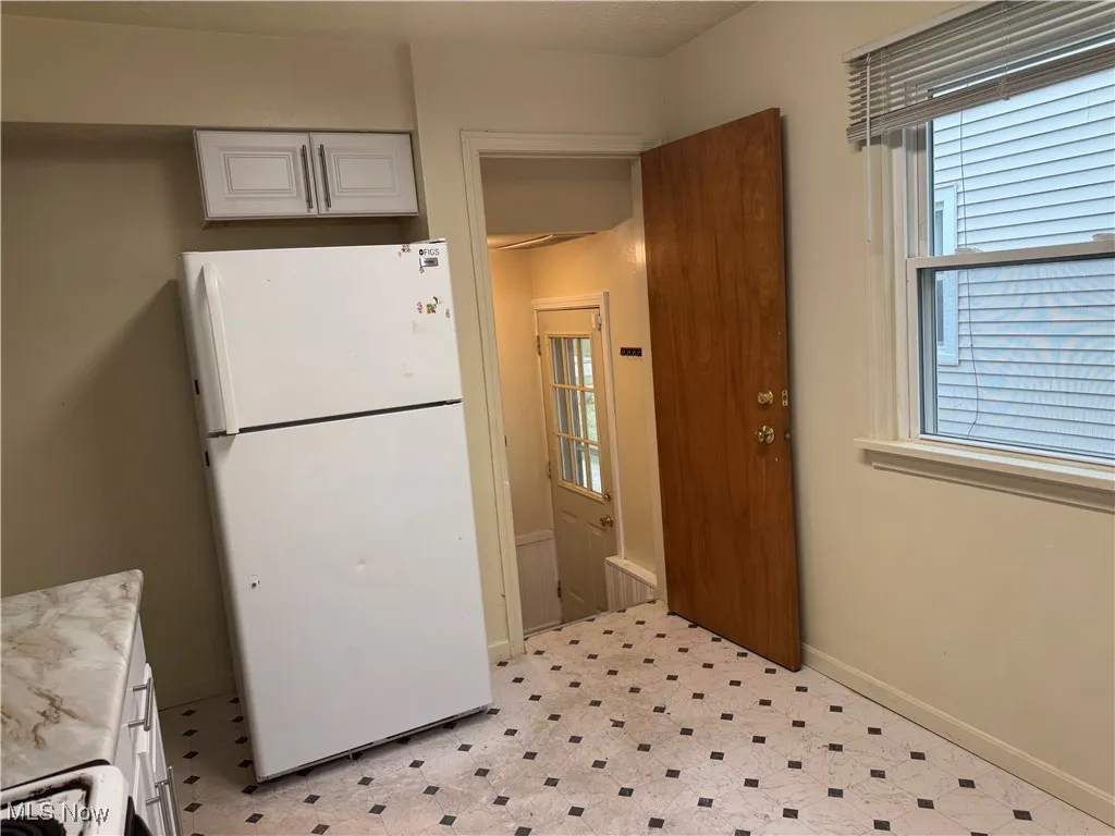 Kitchen featuring freestanding refrigerator, white cabinets, light floors, and light countertops