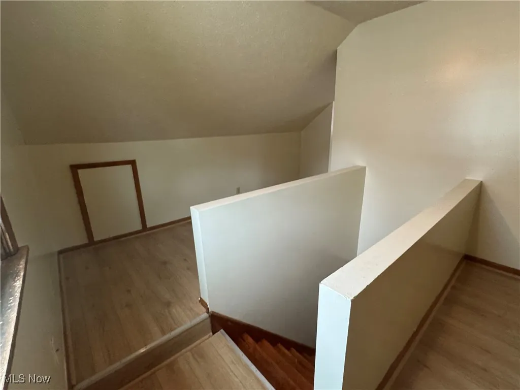 Staircase featuring lofted ceiling, wood finished floors, and a textured ceiling
