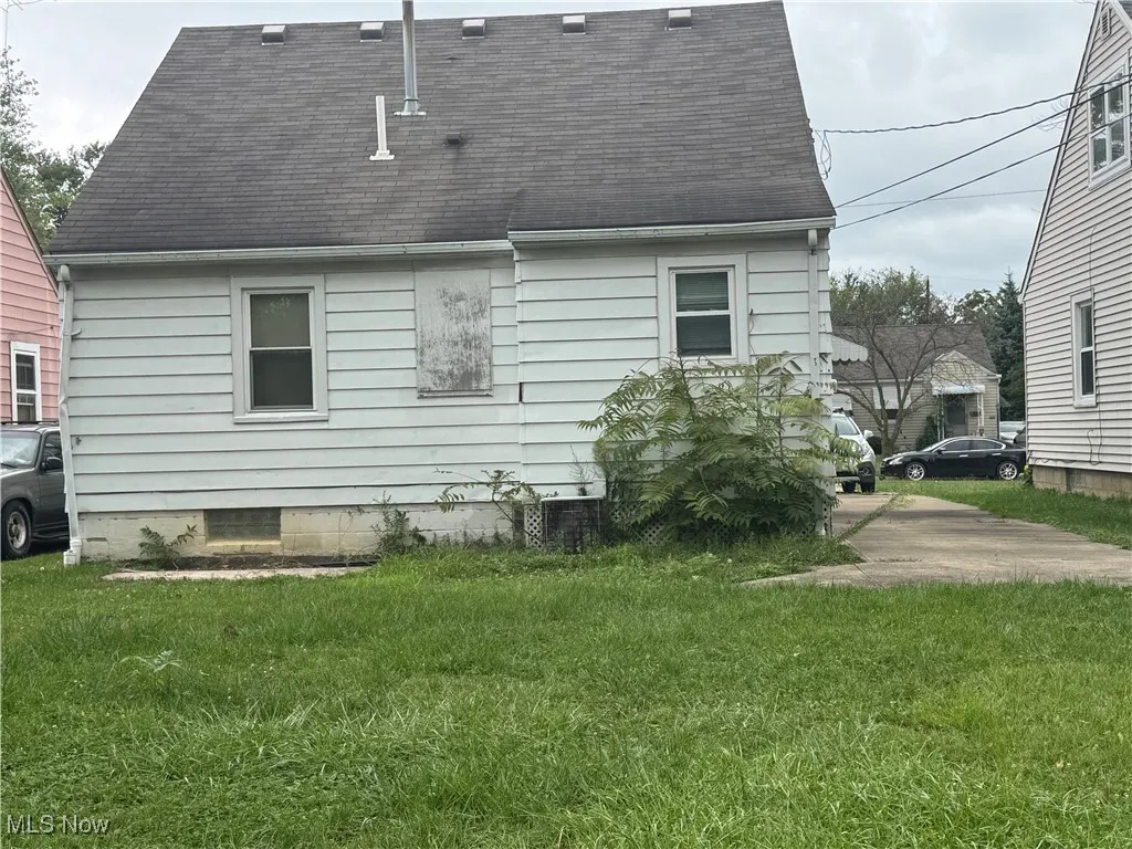 View of side of property featuring roof with shingles and a yard