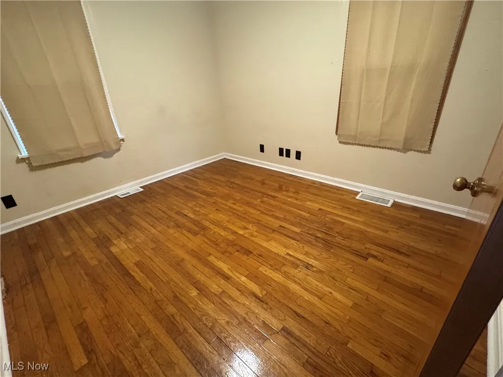 Spare room featuring dark wood finished floors and baseboards