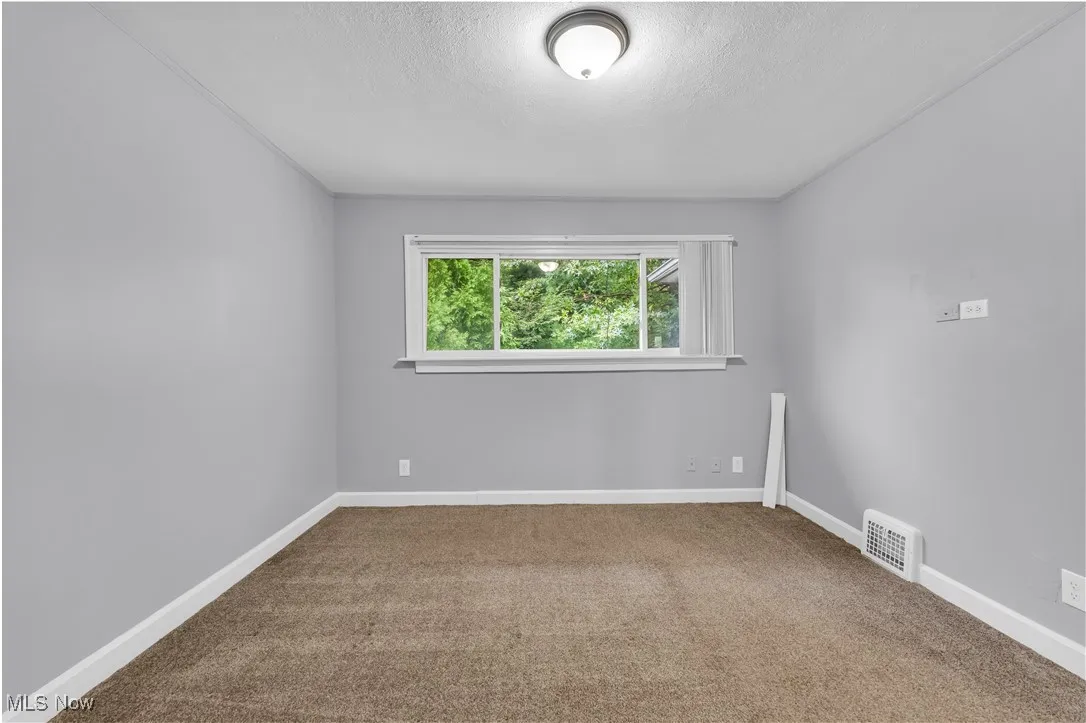 Carpeted spare room featuring baseboards and a textured ceiling