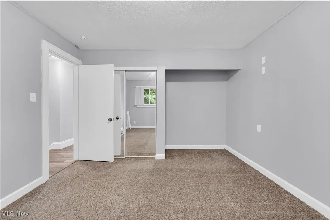 Unfurnished bedroom featuring light carpet, a textured ceiling, and two closets