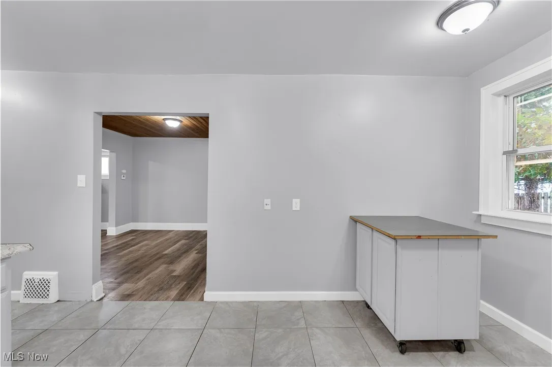 Empty room featuring light tile patterned flooring and wooden ceiling