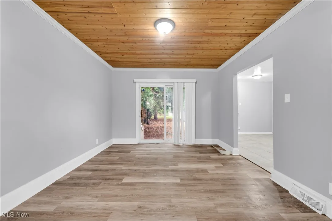Spare room featuring crown molding, wood ceiling, and light wood-style floors