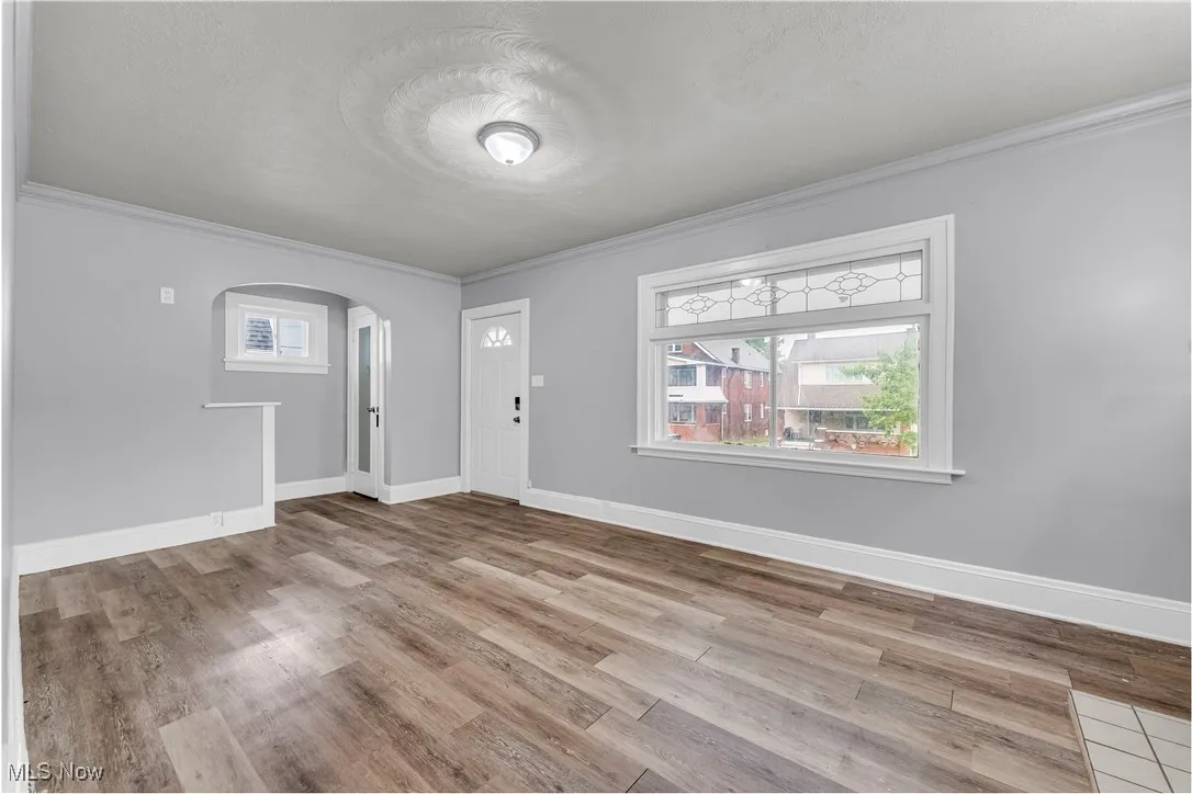Entrance foyer featuring crown molding, arched walkways, healthy amount of natural light, light wood-style flooring, and a textured​​‌​​​​‌​​‌‌​‌‌​​​‌‌​‌​‌​‌​​​‌​​ ceiling