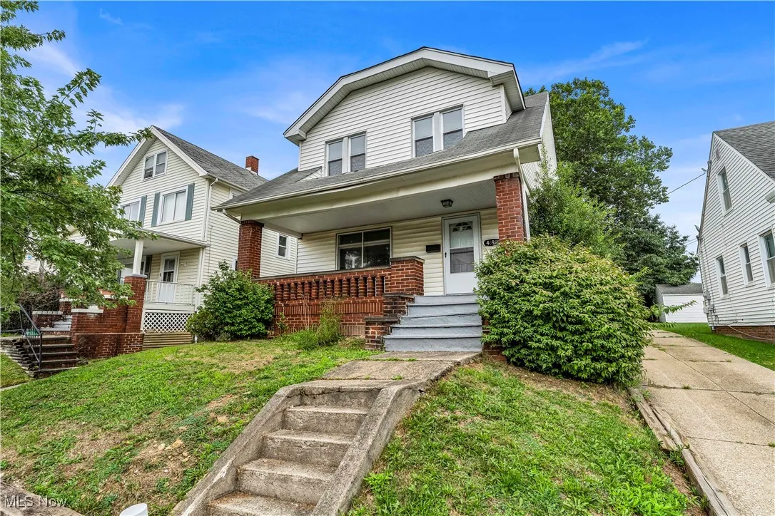 View of front of home featuring brick siding, covered porch, roof with shingles, and a front yard