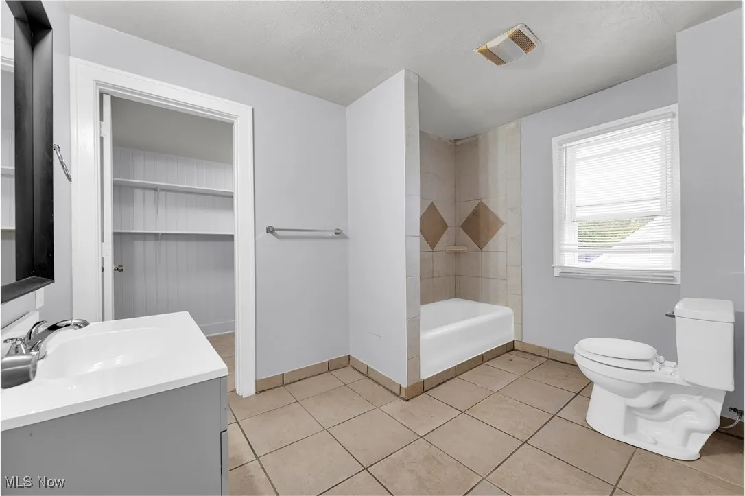 Bathroom with vanity, light tile patterned floors, and  shower combination