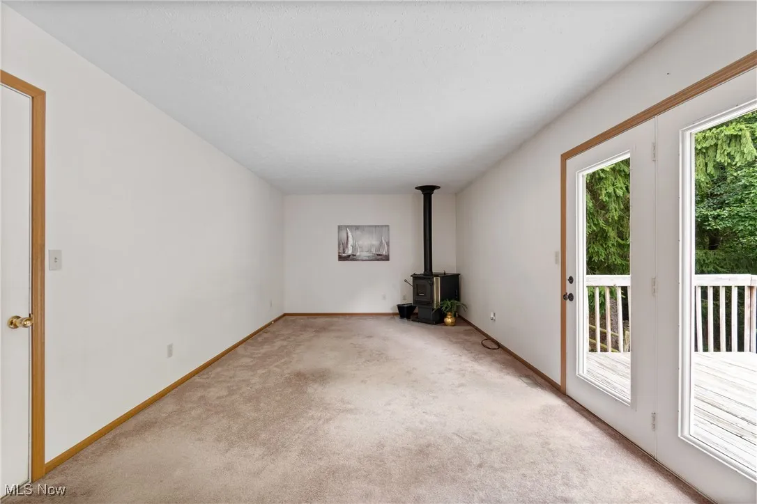 Unfurnished living room featuring a wood stove and carpet floors