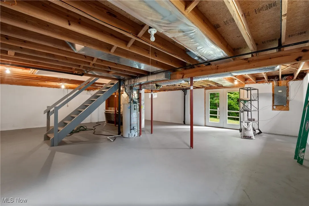 Below grade area with stairs, electric panel, and water heater