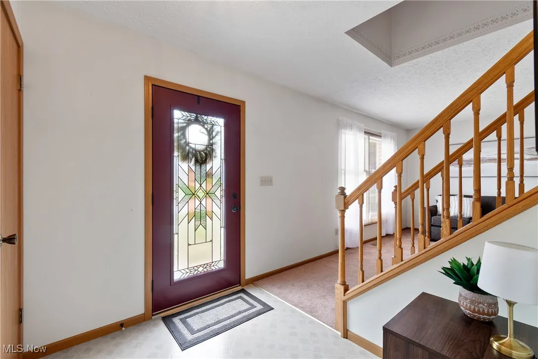 Entrance foyer featuring stairs, carpet flooring, and a textured ceiling