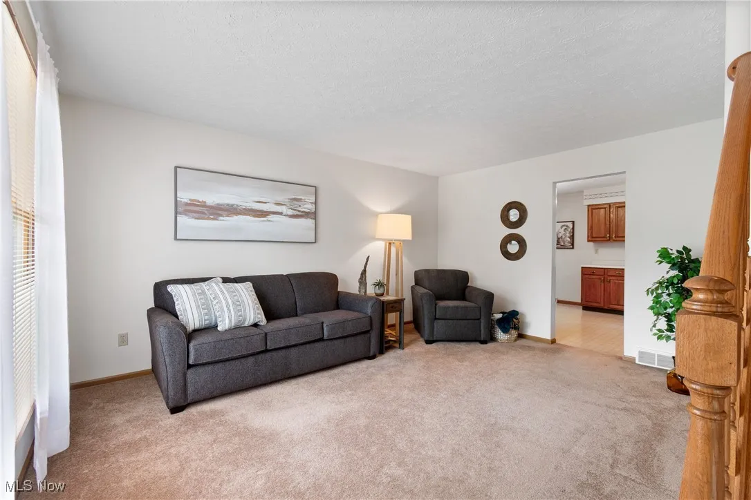 Living area featuring light colored carpet and a textured ceiling