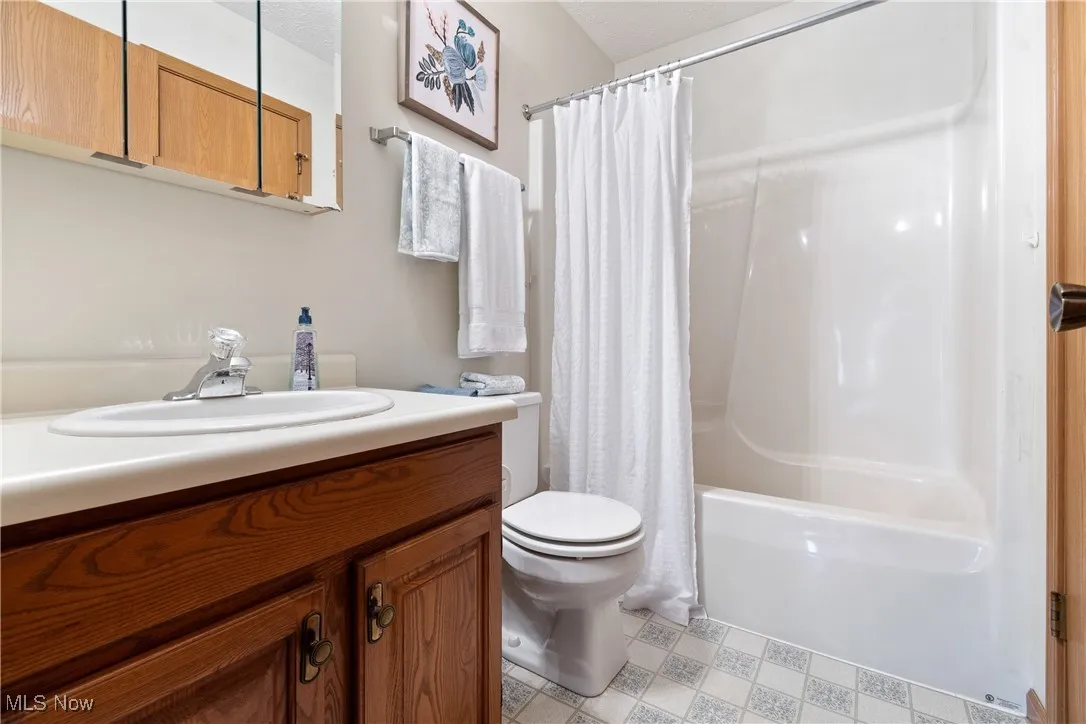 Bathroom with vanity, shower / tub combo, and a textured ceiling