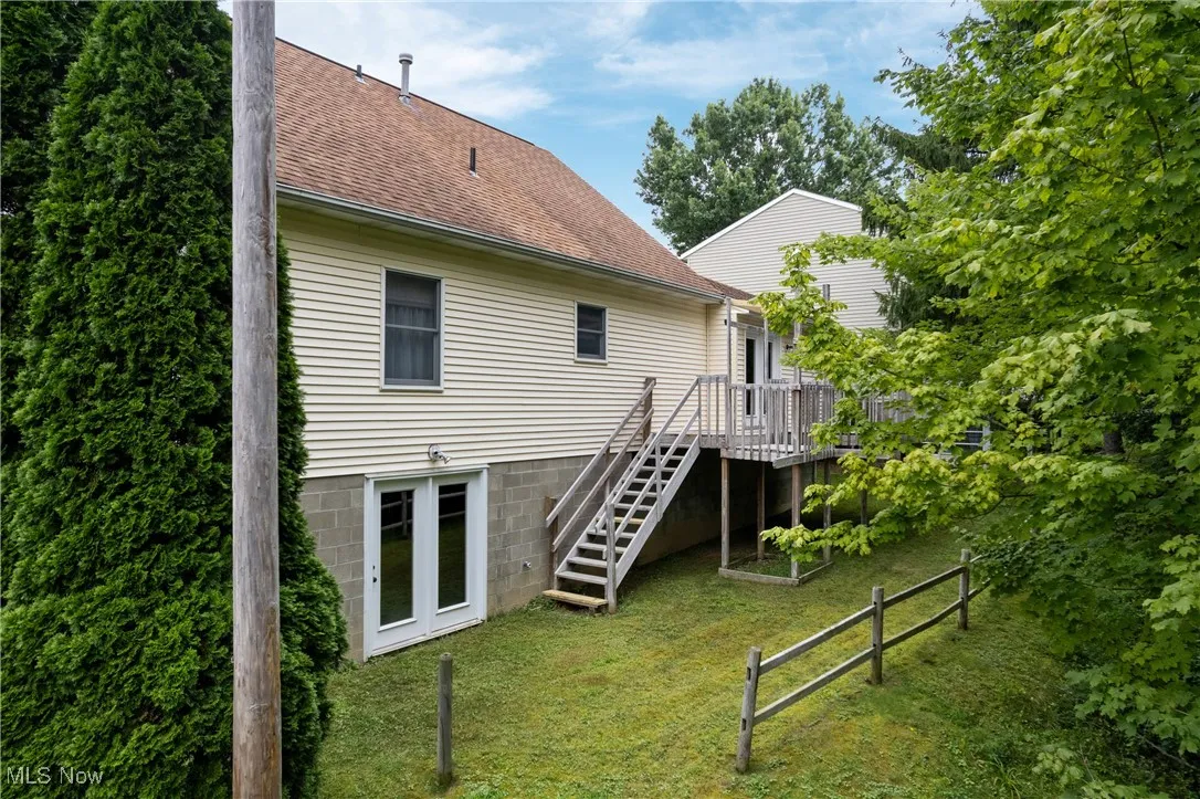 Back of property with stairs, a lawn, a shingled roof, and a chimney