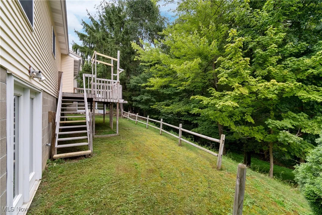 View of yard featuring stairs, a wooden deck, and view of scattered trees