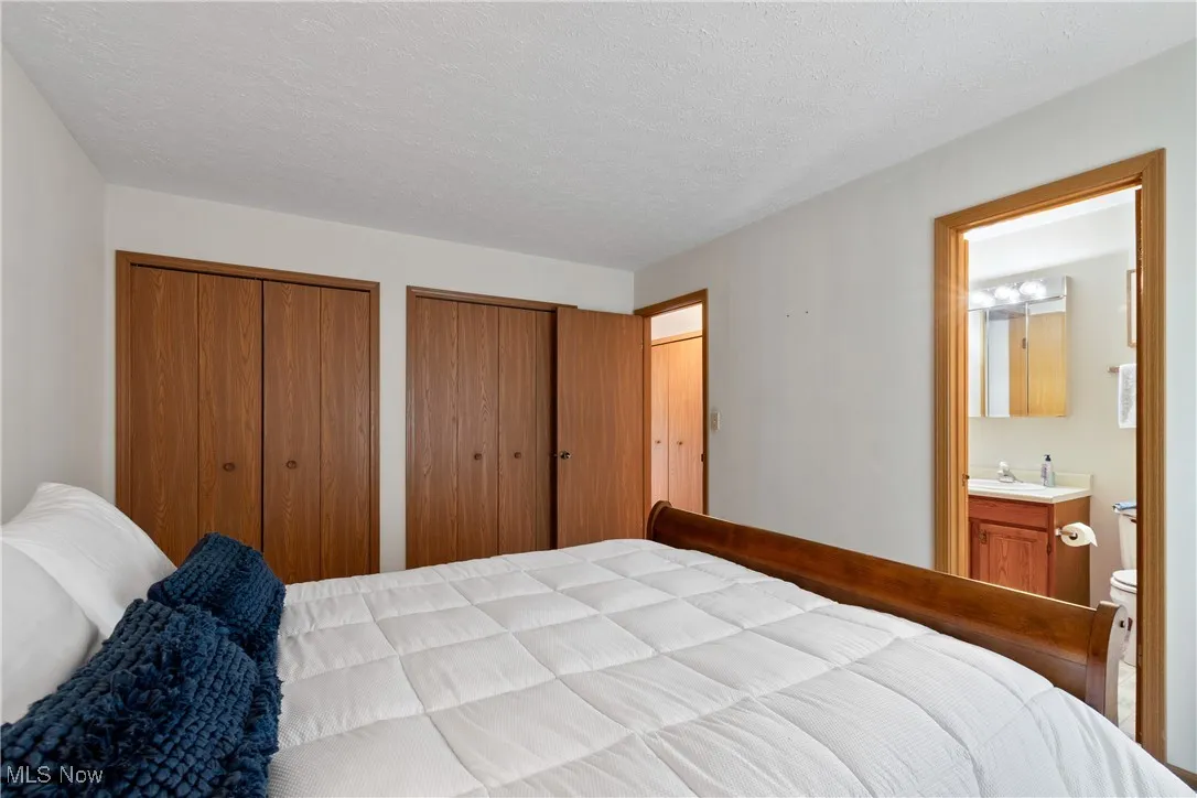 Bedroom featuring two closets, a textured ceiling, and connected bathroom
