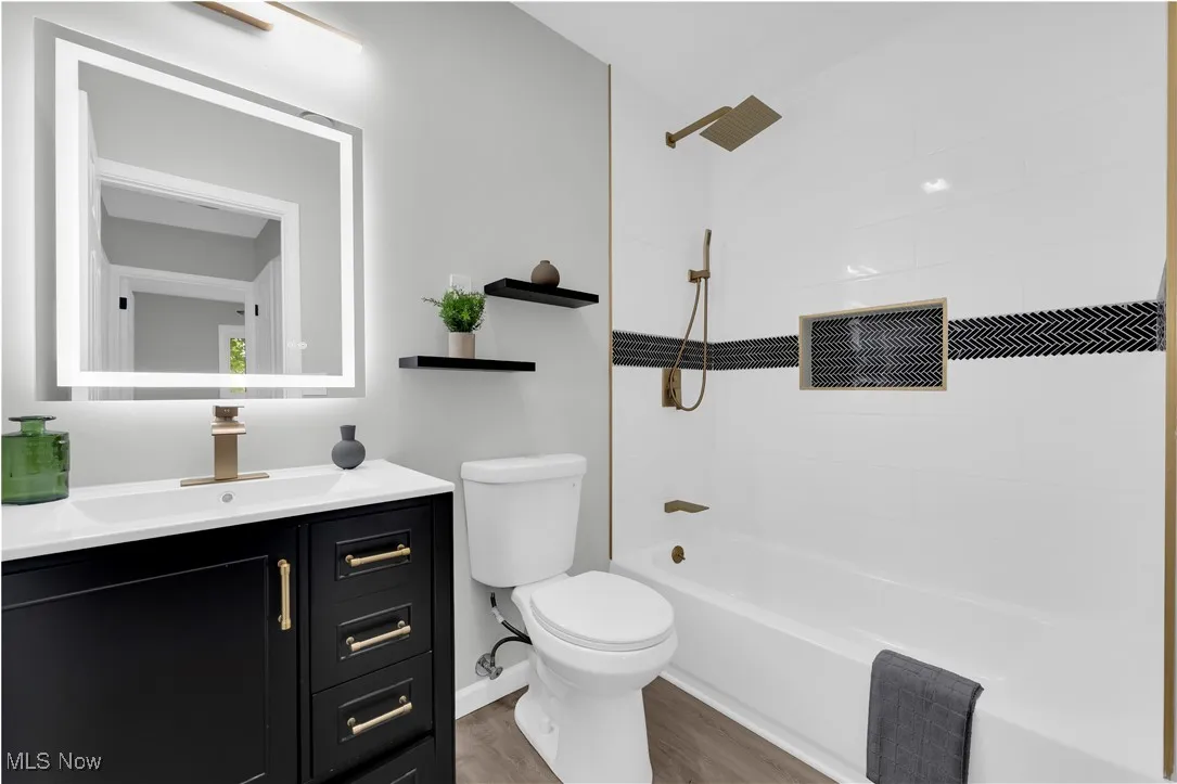 Bathroom featuring shower / washtub combination, vanity, and light wood-style flooring