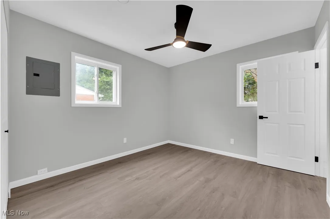 Unfurnished room featuring electric panel, light wood-type flooring, and a ceiling fan
