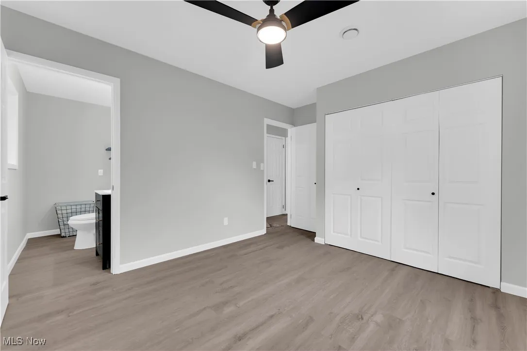Unfurnished bedroom with light wood-type flooring, ceiling fan, and a closet