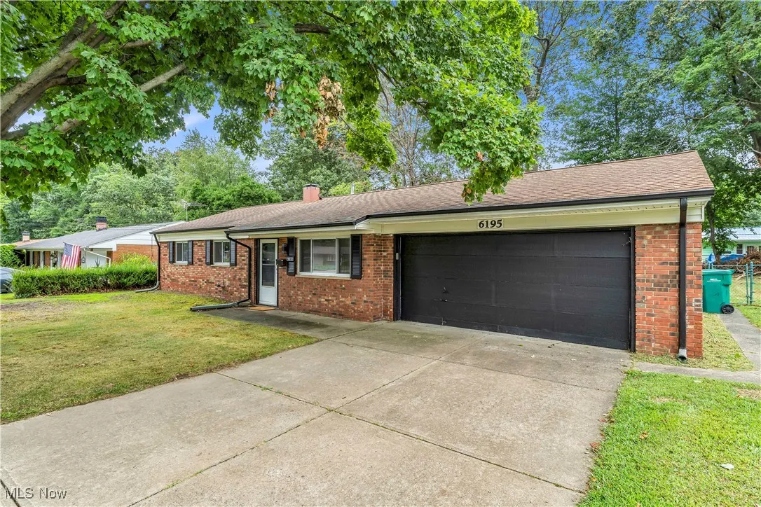Ranch-style house with a garage, a chimney, a front yard, and brick siding